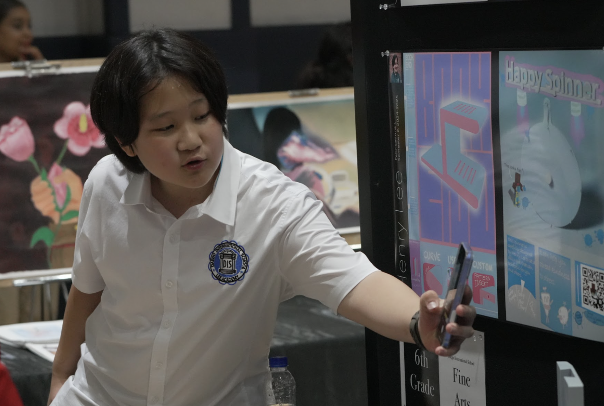 With evident enthusiasm, sixth grader Henry Lee captures a photo of the design exhibit concept, “Happy Spinner.” His curiosity reflects a genuine passion for creativity and design. 